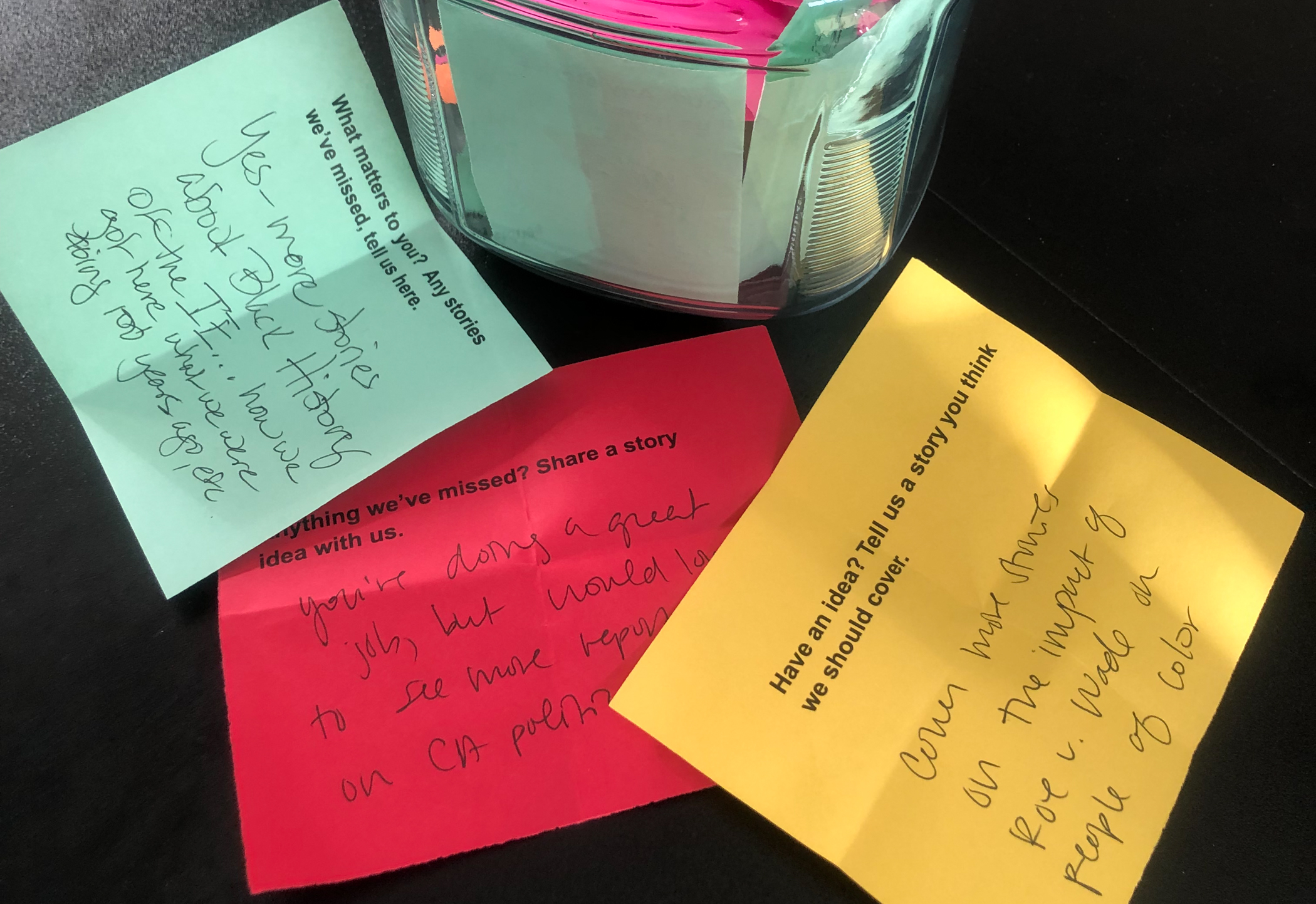 A photo of blue, red, and yellow slips of paper with the prompt "What matters to you? Any stories we've missed, tell us here." and written-in suggestions