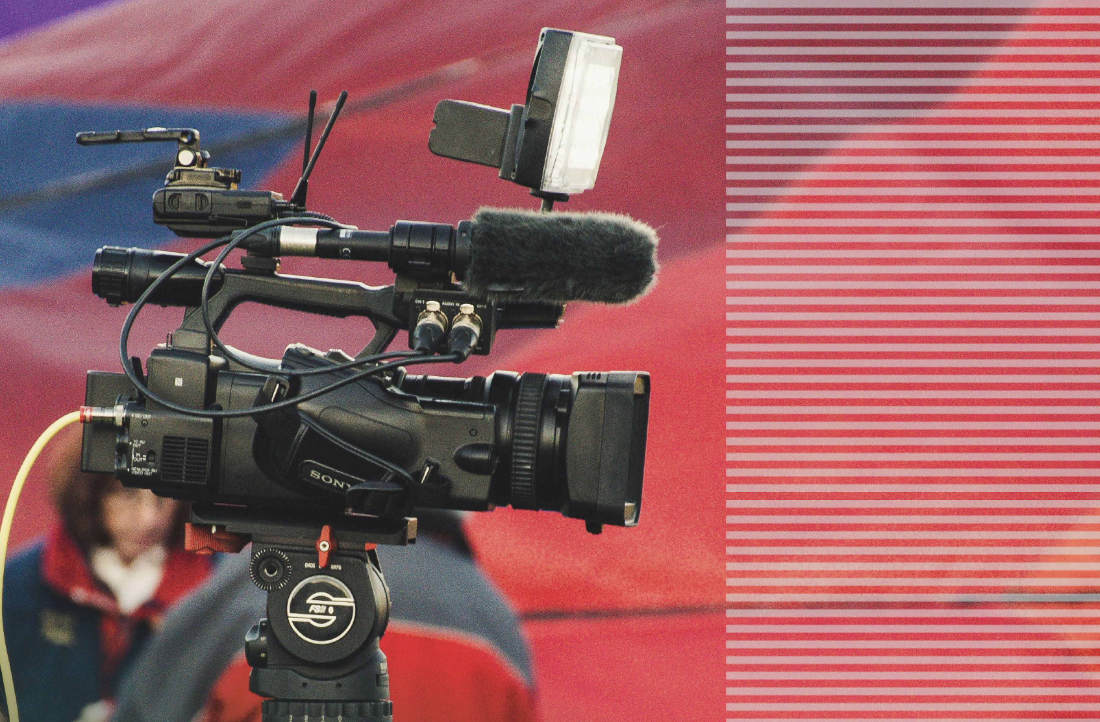 A photo of a news camera with a red background