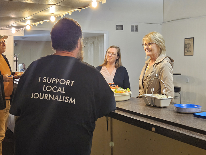 Publisher Joey Young (back turned) talks to Press Club members at the Harvey County Now office during a Thursday night mingle.